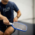 Person holding a FLiK Falcon pickleball paddle with 'Flik' branding in a casual setting