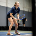 Woman playing pickleball on an indoor court, holding a Flik Falcon paddle.