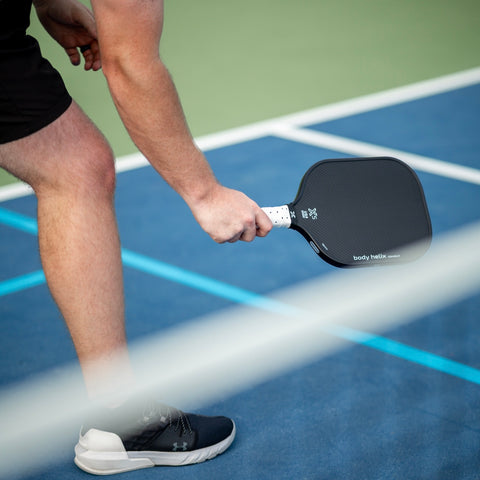 Person holding an body helix X5 pickleball paddle on a court